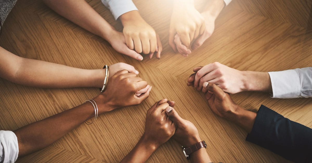 diverse group of hands joined together at table